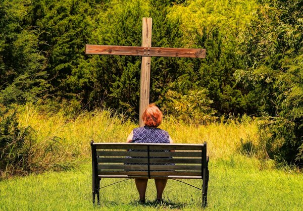 woman sitting in front of a cross