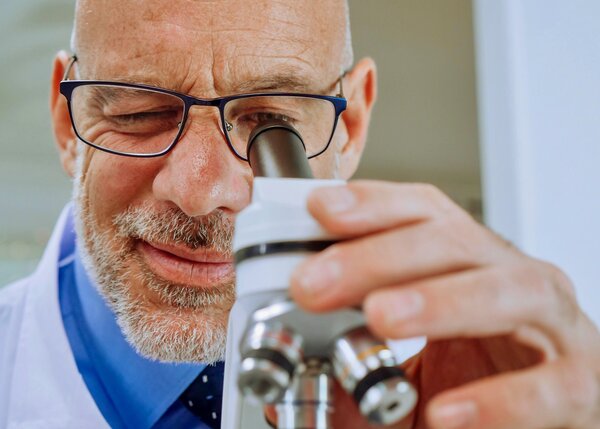 Man looking through microscope for small errors