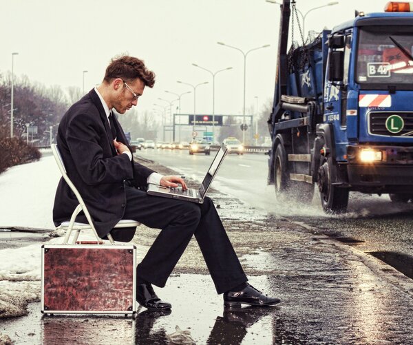 Man working on laptop on side of road