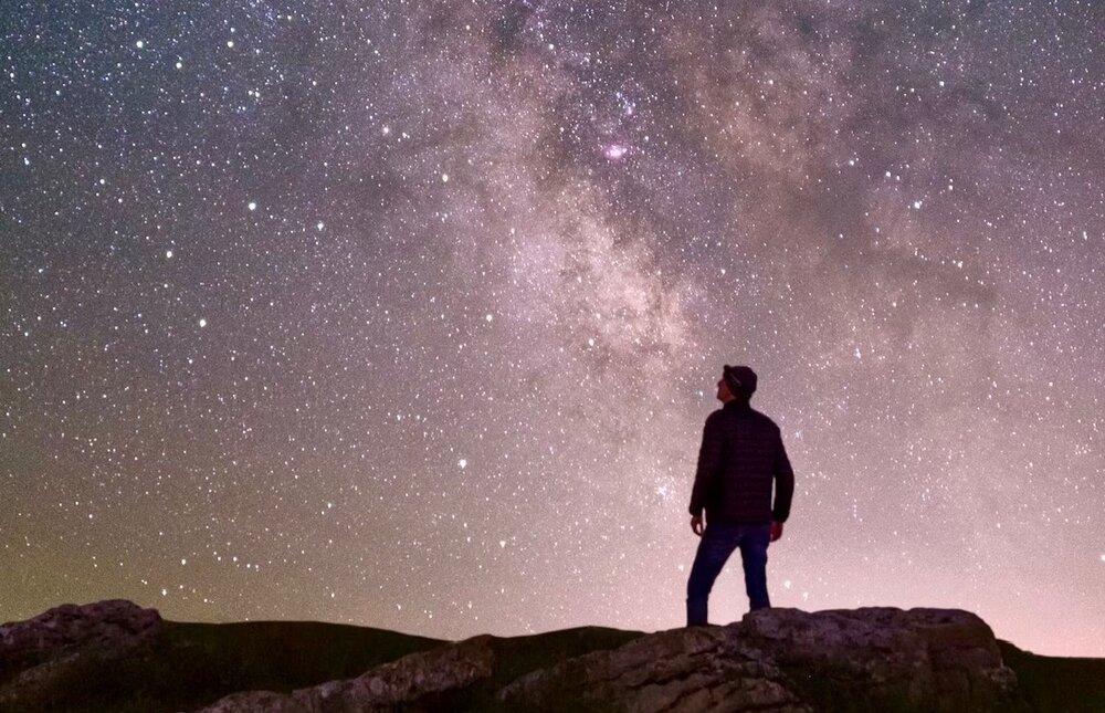 Man looking at stars and seeing the effects of the past